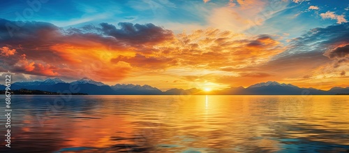 Golden clouds mirror in the water during a vibrant sunset on Lake Geneva in Switzerland Copy space image Place for adding text or design © HN Works