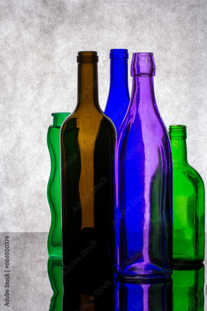 Still life with colored glass bottles on a gray background Still life with colored glass bottles on a gray background