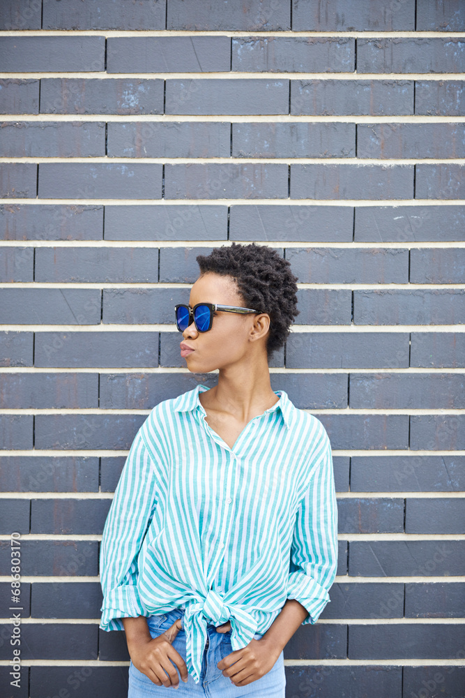 Woman with sunglasses standing in front of grey facade waiting