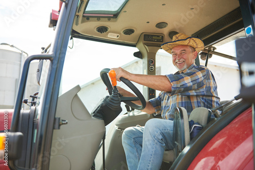 Portrait of smiling senior farmer on tractor