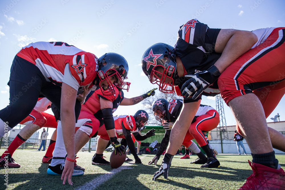 American football players on the line of scrimmage during a match American football players on the line of scrimmage during a match