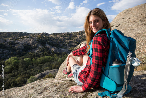 Spain, Madrid, smiling young woman resting on a rock during a trekking day