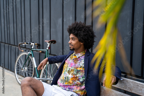 Stylish man with bicycle sitting on a bench photo