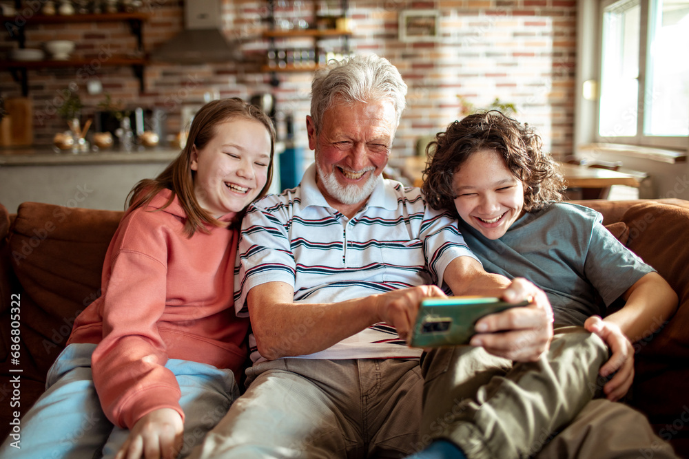 Grandfather and Grandchildren Sharing a Laugh While Looking at Phone