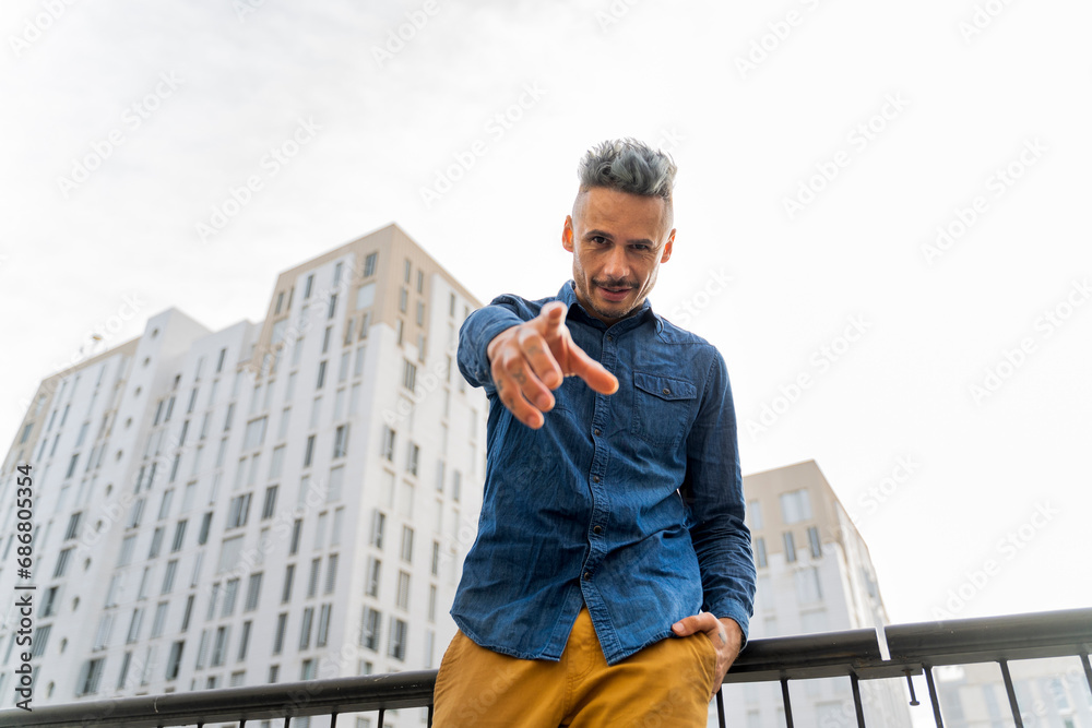Confident man pointing while standing against sky