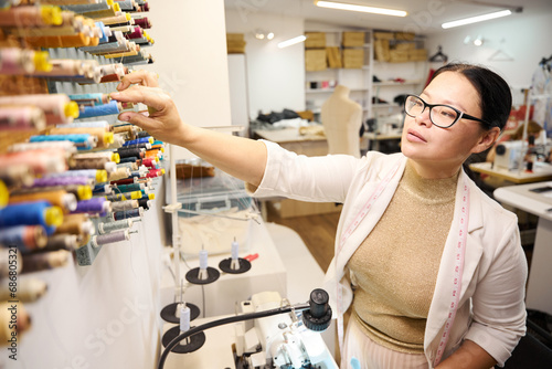 Woman selects a spool of thread at a special stand