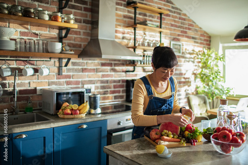 Woman Preparing Healthy Meal in Kitchen with Fresh Fruits and Vegetables photo