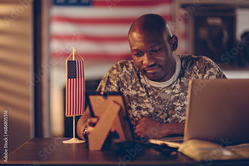 African American soldier holding picture of his family at army base