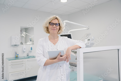 Female densit standing in clinic, holding digital tablet