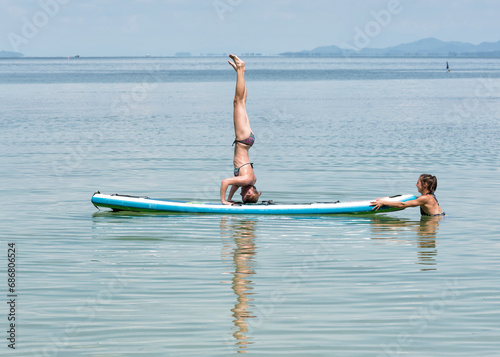 Thailand, Krabi, Lao Liang, woman doing a headstand on SUP Board in the ocean photo