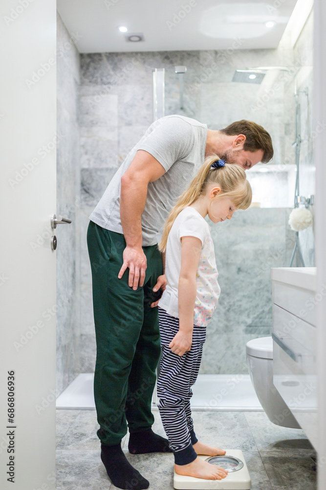 Father and daughter checking weight on bathroom scales