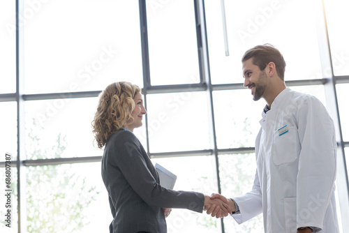 Businesswoman and doctor shaking hands in hospital photo