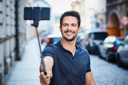 Man taking photo with smartphone mounted on selfie stick photo