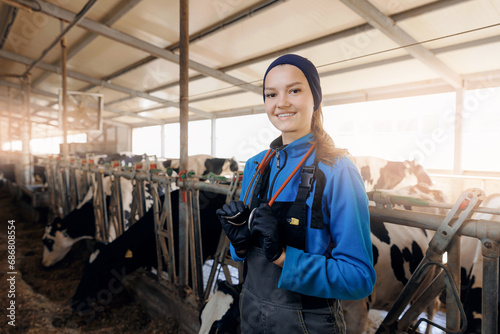 Concept banner vet worker of livestock farm. Portrait happy young woman veterinarian with phonendoscope on background milk cows © Parilov