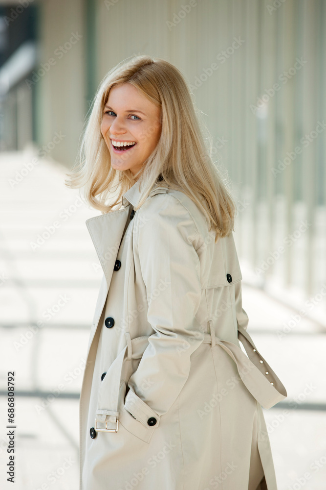 Portrait of laughing blond woman wearing trench coat