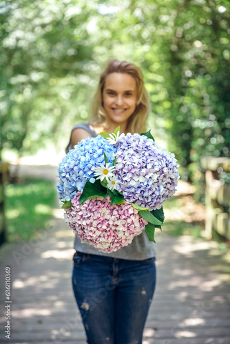 Smiling young woman showing a bouquet of hydrangeas and daisies