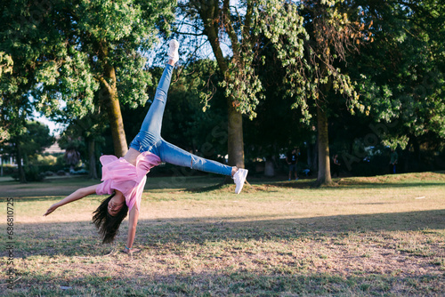 Girl doing cartwheel on land against trees in park photo