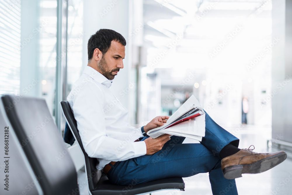 Businessman reading a newspaper in waiting hall Businessman reading a newspaper in waiting hall