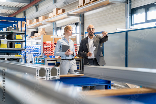 Businessman talking to businesswoman in factory