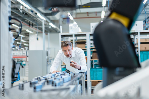 Businessman in a modern factory hall examiming workpieces photo