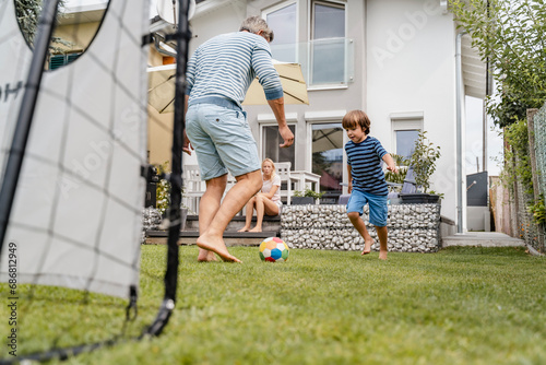 Father and son playing football in garden