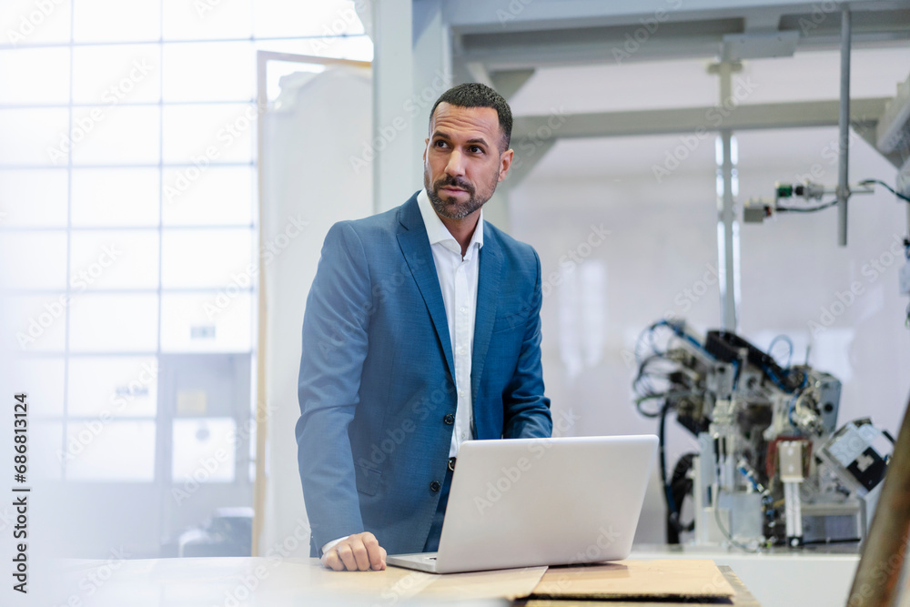 Businessman using laptop in a factory Businessman using laptop in a factory