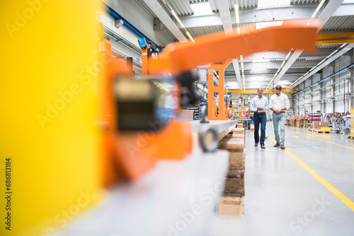 Two men walking and talking on factory shop floor