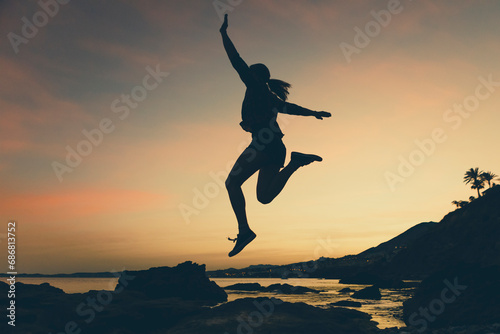 Silhouette of jumping woman at beach during sunset