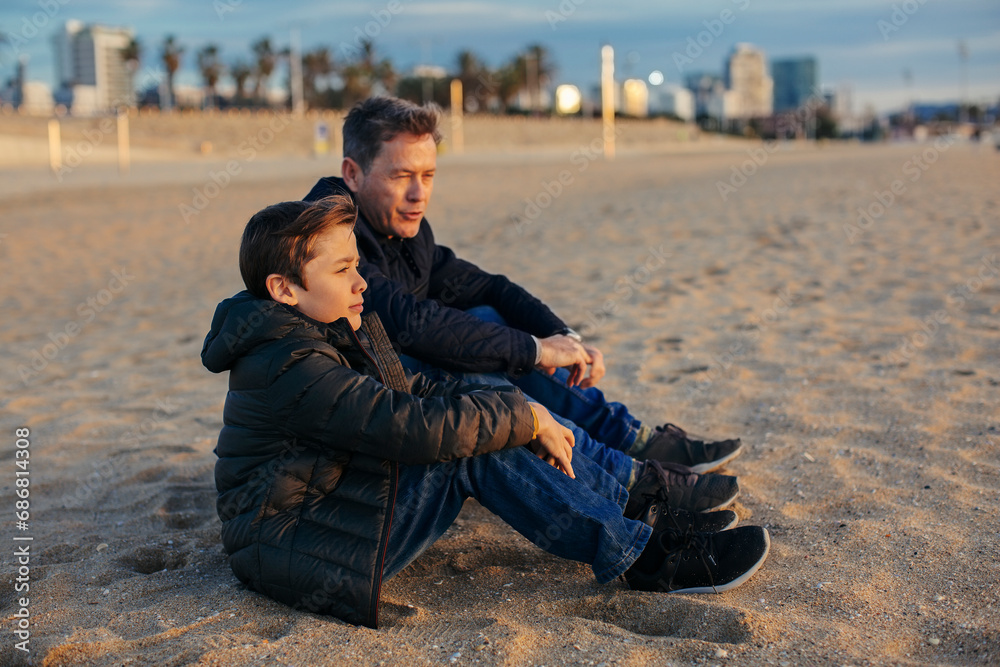 Father and son sitting on the beach