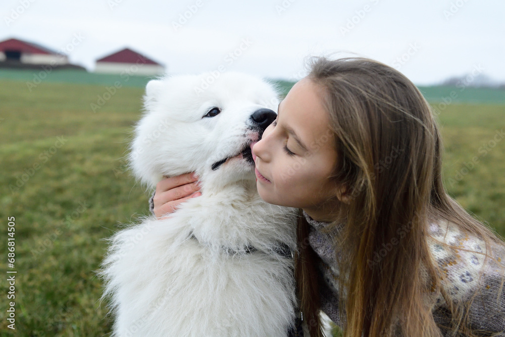 Girl and her white dog cuddling on a meadow Girl and her white dog cuddling on a meadow