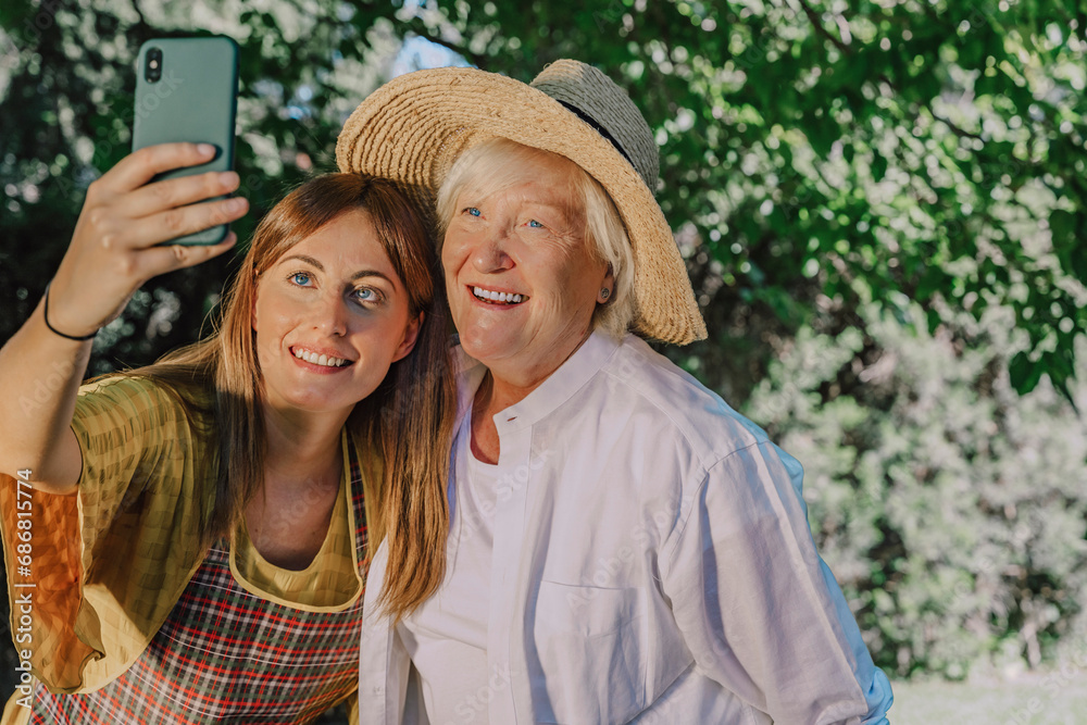 Smiling mid adult woman taking selfie with mother in yard