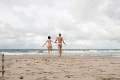 Obraz na płótnie Nude couple running to the sea, holding hands w salonie