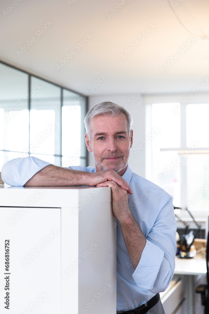 Successful businessman in his office, looking confident Successful businessman in his office, looking confident