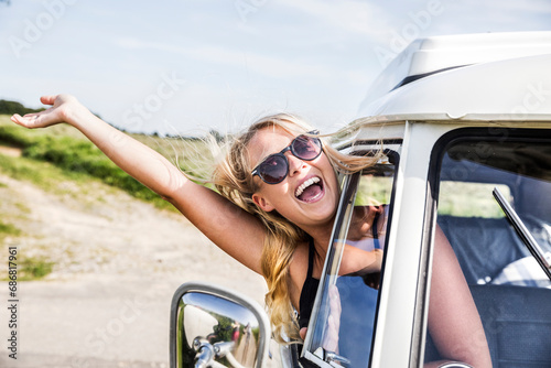 Carefree woman leaning out of window of a van