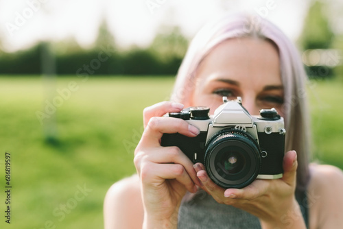 Young woman taking pictures with camera in nature