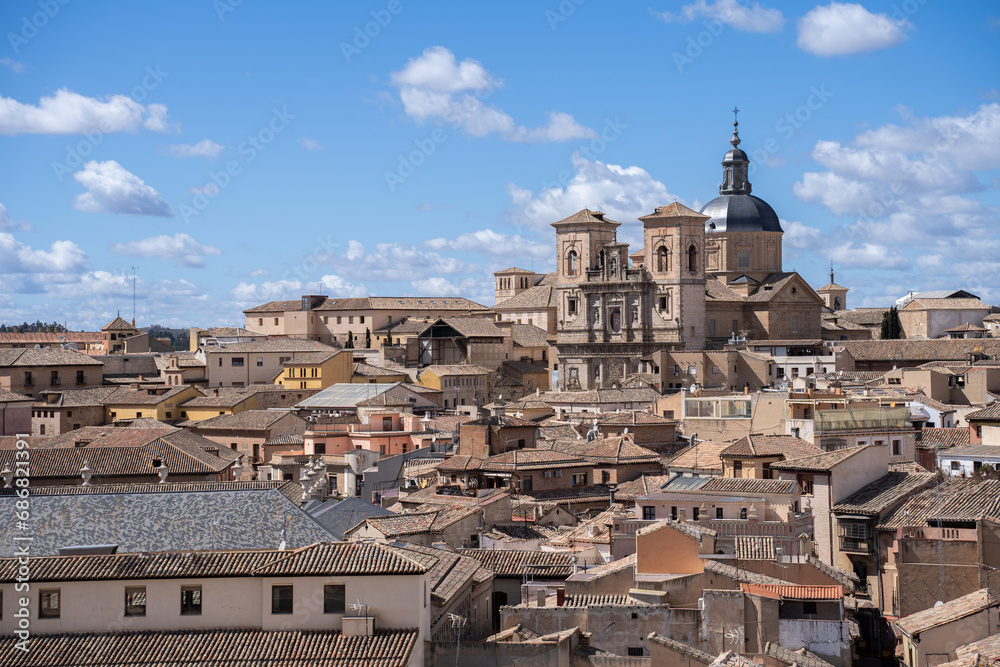 Jesuit Church of San Ildefonso seen between the rooftops of the city of Toledo, Spain, on a sunny day with few clouds