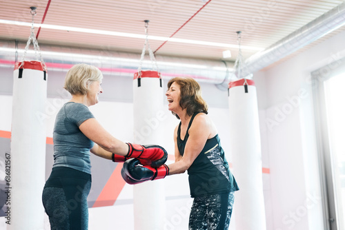 Two happy senior women with boxing gloves in gym photo