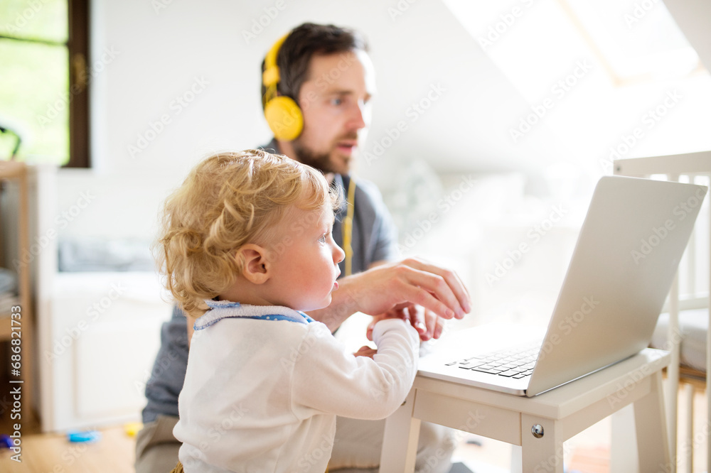 Father at home with his little son using laptop Father at home with his little son using laptop