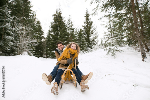 Obraz na plátně Happy young couple on sledge in winter forest