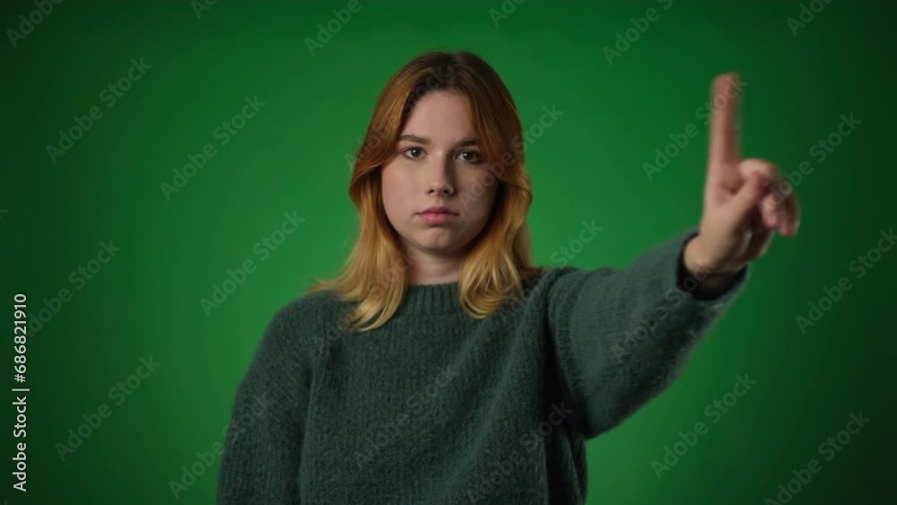 Upset Caucasian Woman Wagging Finger in Disapproval on Green Background