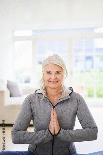 Smiling senior woman with hands clasped exercising at home