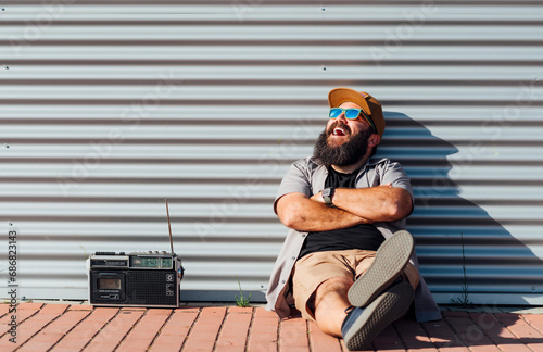Portrait of bearded man with portable radio enjoying sunlight photo