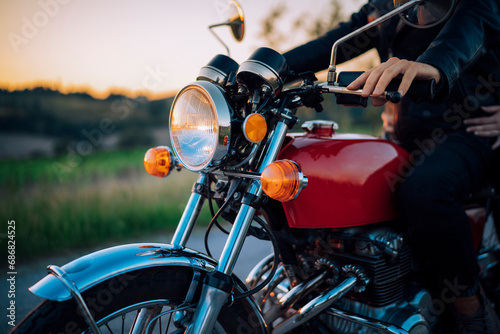 Crop shot of couple on vintage motorbike at sunset