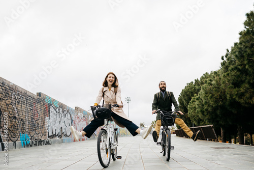 Carefree couple riding e-bikes on a promenade