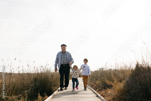 Grandfather and grandchildren strolling hand in hand on boardwalk photo