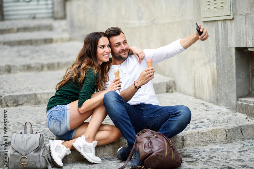 Tourist couple with ice cream cones in the city taking a selfie