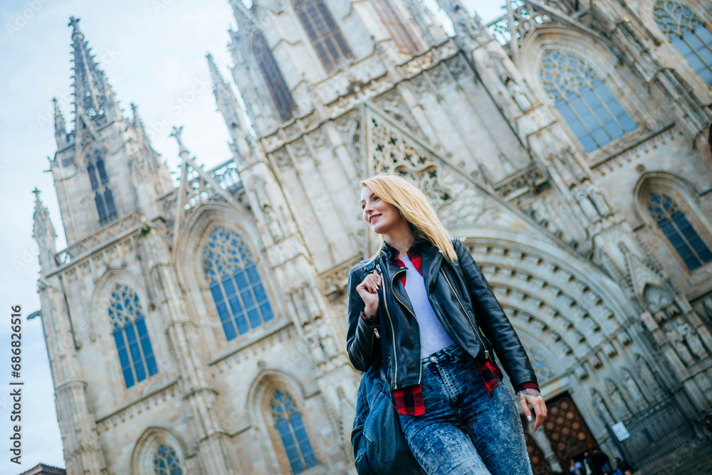 Spain, Barcelona, smiling young woman walking in front of cathedral