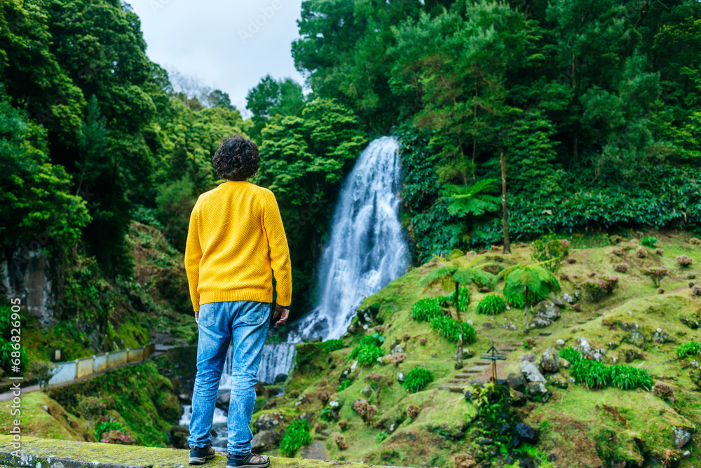Azores, Sao Miguel, rear view of man looking at a waterfall in the Ribeira dos Caldeiroes Natural Park