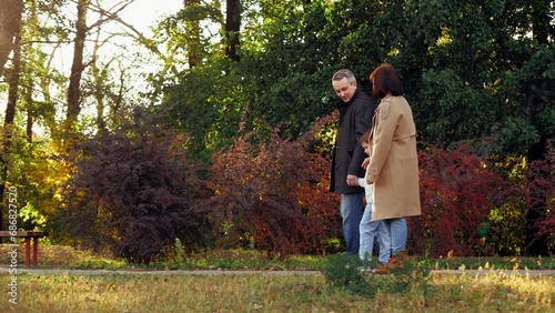 Delighted family spends weekend together walking through autumn botanical garden