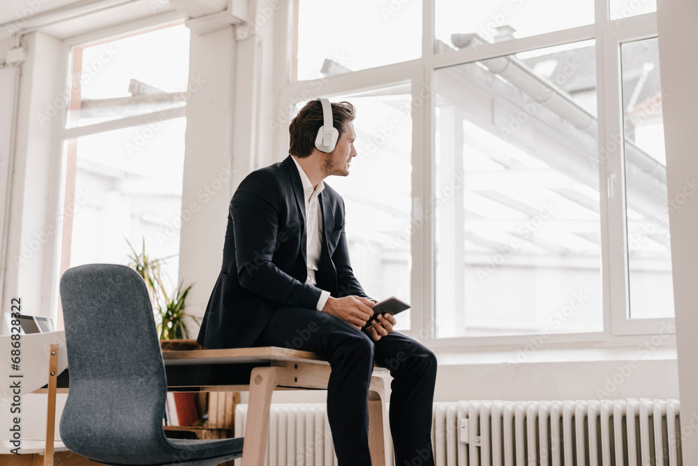 Businessman with tablet and headphones sitting on table Businessman with tablet and headphones sitting on table